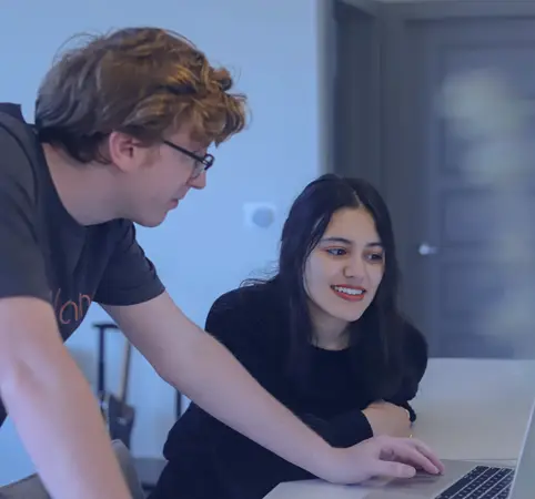 Dos personas colaboran frente a una laptop, sonrientes y concentradas. Dos personas colaboran frente a una laptop, sonrientes y concentradas.